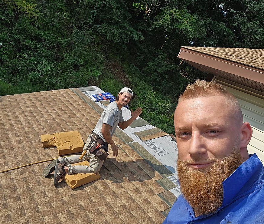 Two roofers working on a residential shingle roof